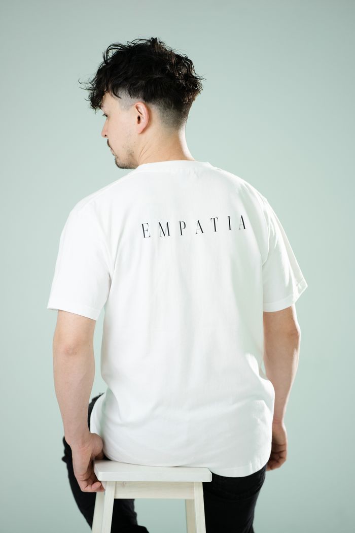 背中に EMPATIA のロゴが入った白のTシャツ(別カット)